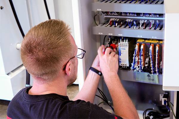 Methods technician works on electrical system of a CNC machine.