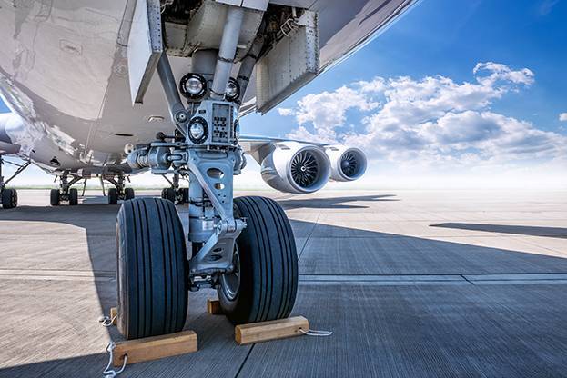 the landing gear of an airplane on a runway tarmac representing aerospace manufacturers