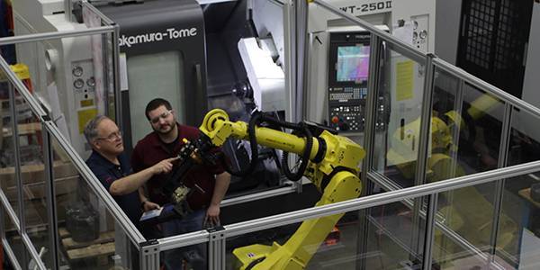 two engineers examine a Fanuc automated robotic arm inside a cnc machining solution